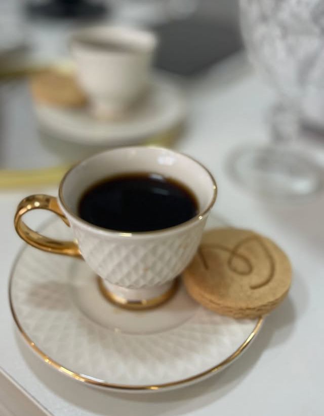 Café em xícara de porcelana com biscoito estampado com o monograma