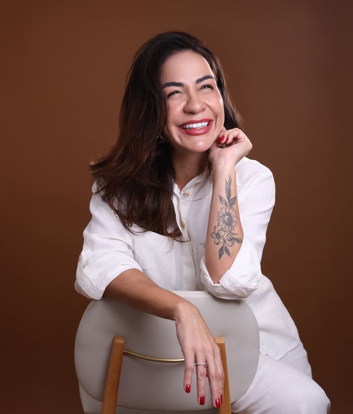 Dra. Mayara Justo sorrindo, sentada em uma cadeira